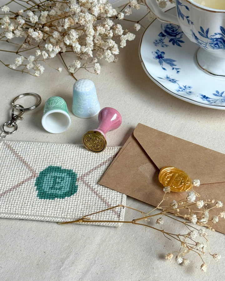 Love letter needlepoint bag charm finished paired next to a look-alike real envelop with stamp