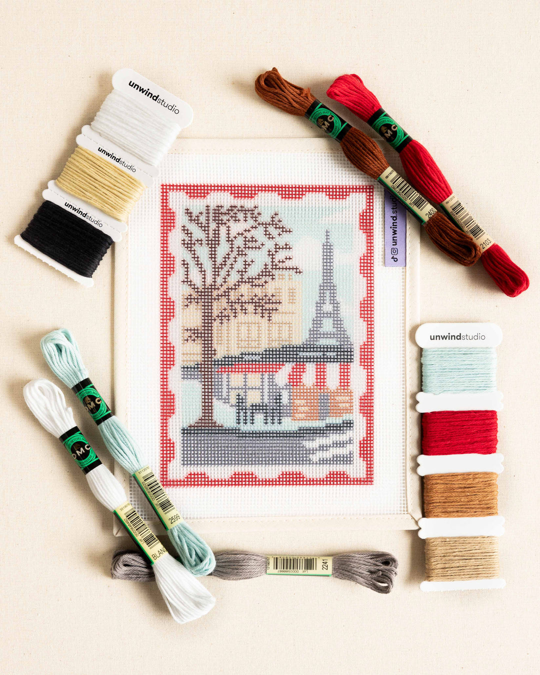 Flat lay of the Paris Stamp/Postcard needlepoint kit with matching dmc soft cotton threads