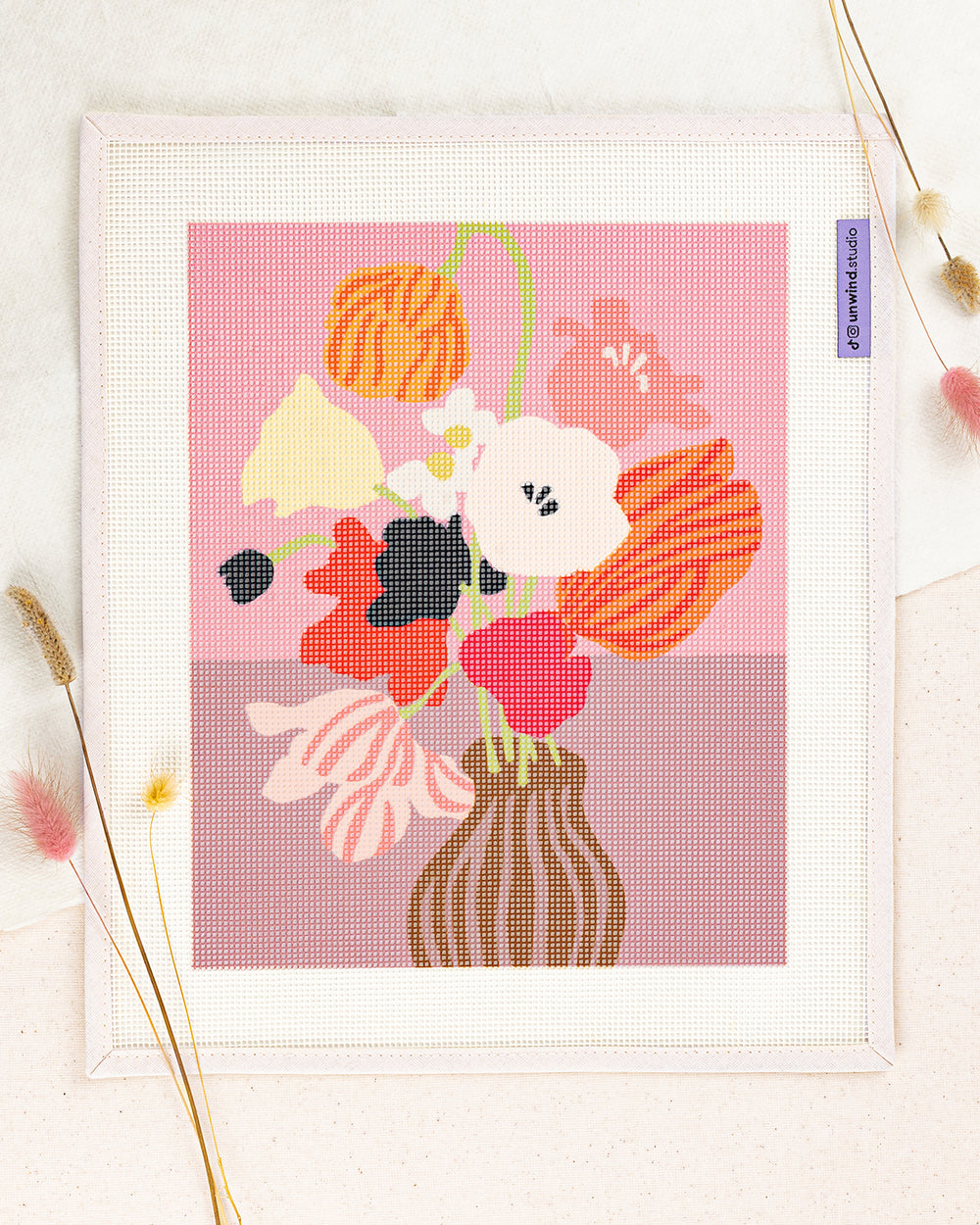 Pink Table needlepoint kit by Ophelia Pang: printed canvas of pink flowers on blue, framed with dried twigs