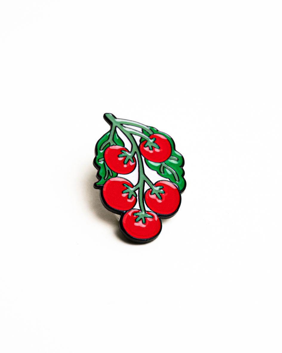 up-close shot of the unwind studio needle minder pomodoro magnet (enamel pin) in a bold red and green color.