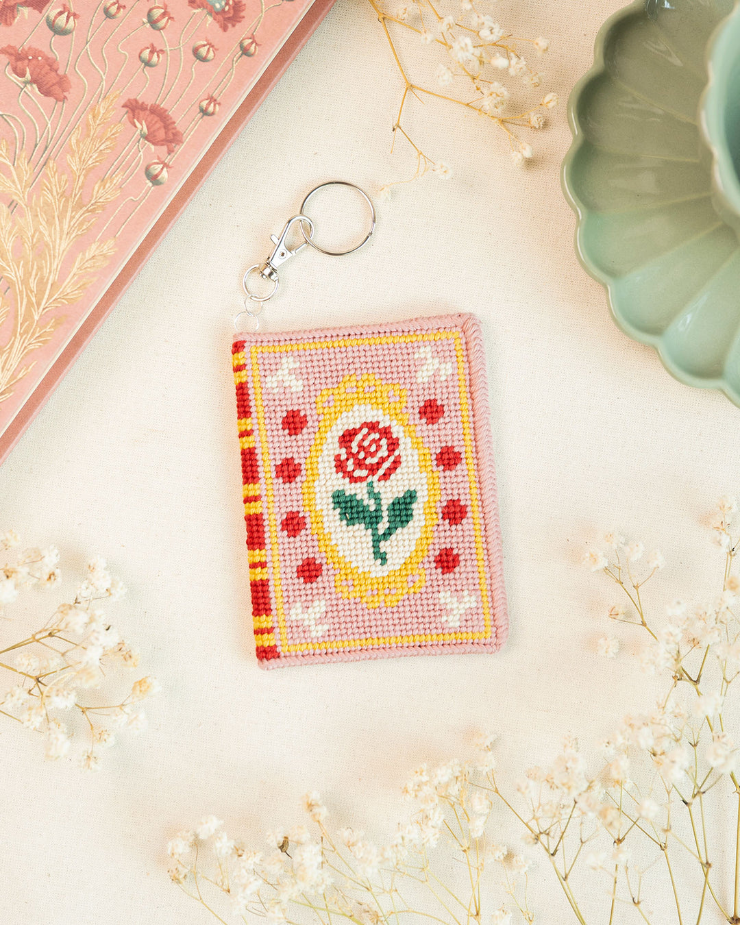Romance book needlepoint bag charm finished and placed next to matching decor elements