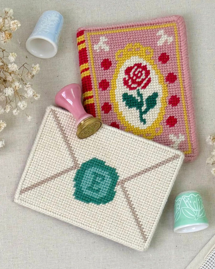 Romance Book needlepoint Bag charm and Love Letter bag needlepoint charm fully finished placed next to each other with matching regency decor elements