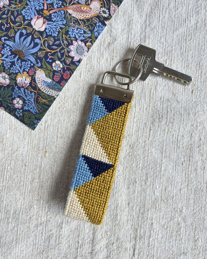 Summit Key Fob with a key placed on top of a linen towel and next to a floral book

