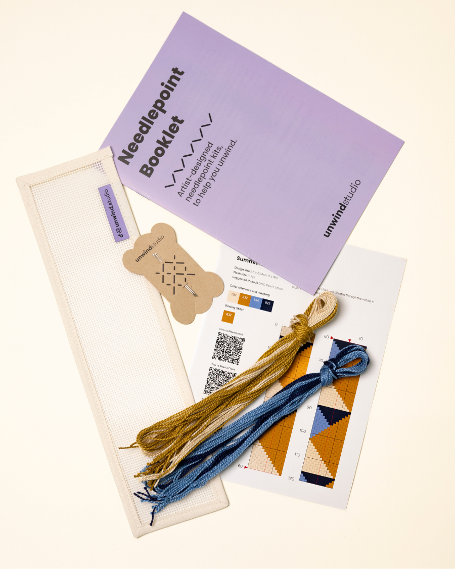 flat view of the Summit Key Fob Needlepoint Kit with blank canvas, matching threads, a instructional booklet and a graphic flyer