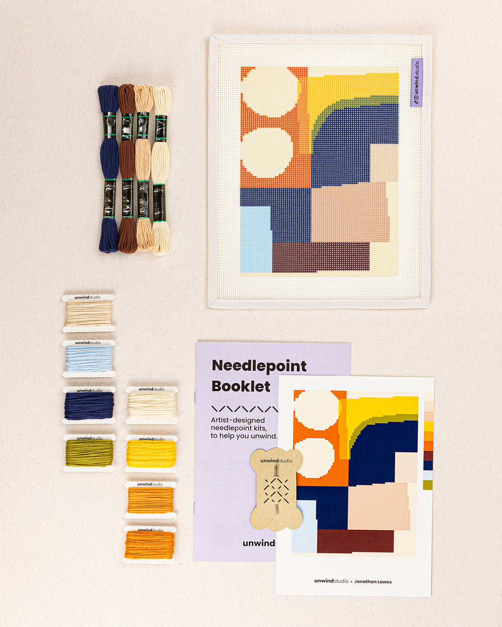 theo needlepoint kit contents: printed canvas, threads, needles, and instruction booklet, graphic flyer laid flat