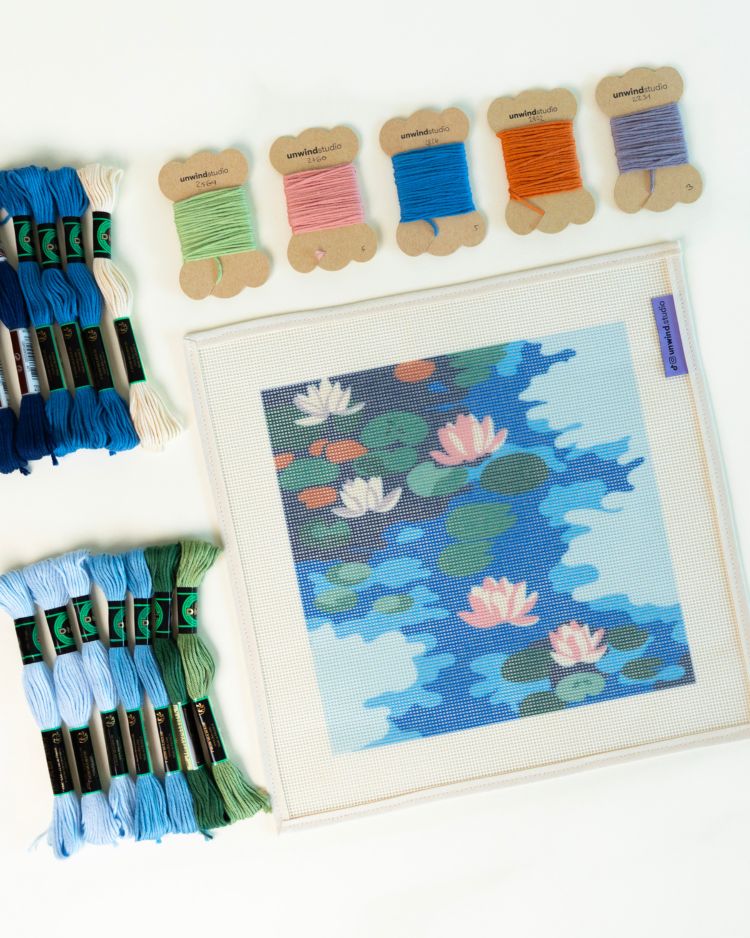 Embroidery kit with cross-stitched piece of water lilies and colorful threads on a white background