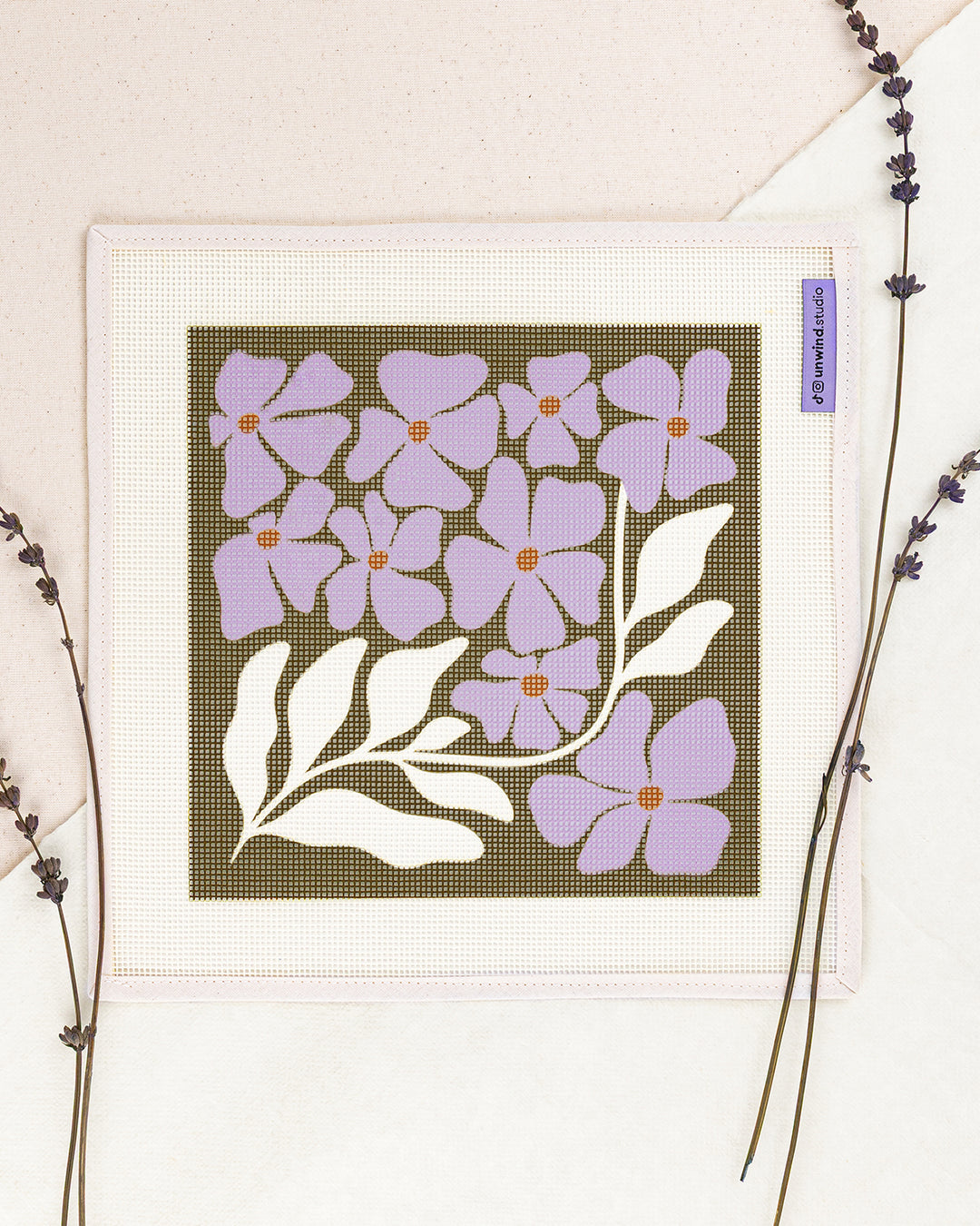 wildflowers needlepoint kit by diana pereira: printed canvas of purple flowers, framed with dried twigs