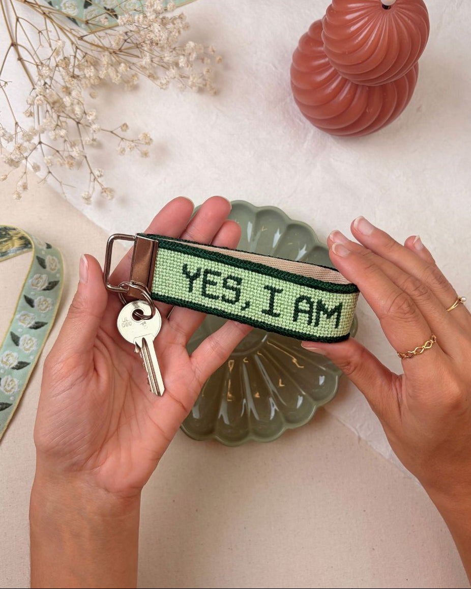 "yes, i am" needlepoint key fob finished with a ket set and matching decorative elements surrounding