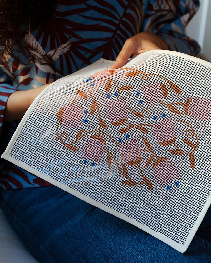 detail of hands stitching bellflower needlepoint canvas