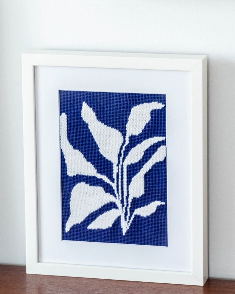 Needlepoint kit with illustration of white plant in blue background